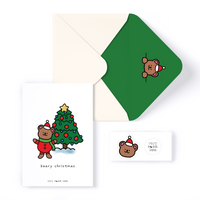 White card with illustration of brown bear in a Santa Suit, next to a Christmas Tree. Card reads "beary christmas"