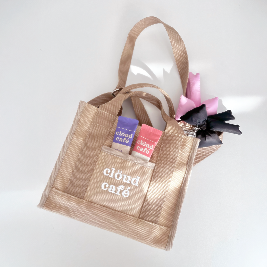 Light tan rectangle canvas tote bag with embroidered "Clöud Café" logo in white. Small pocket in front.