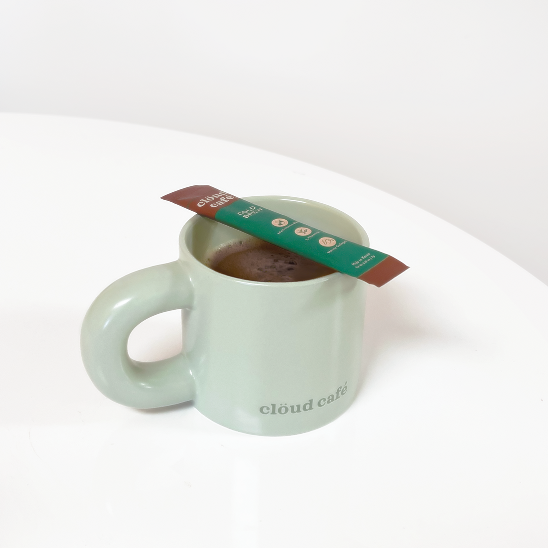 Pastel Green Chunk Mug. Thick rounded handle. Subtle dark green "Clöud Café" logo on bottom front of cup.