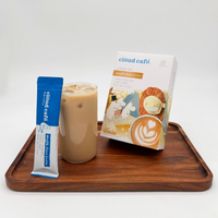 A glass of iced Cloud Cafe Moomin Waffle Cone Latte sits on a wooden tray next to a waffle cone satchet+ a box of Waffle Cone Latte product with a white background.