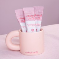 Pink mug with rounded thick handle, and 'cloud café' branding against a light purple background.