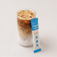 Glass of iced coffee with a Cloud Cafe vanilla latte packet on a white background