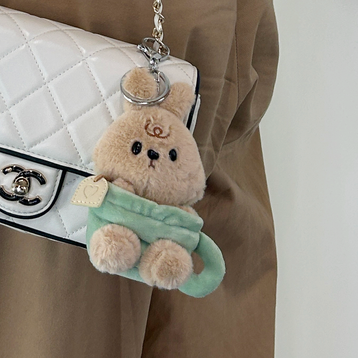 Otto keychain plush attached to white purse in lifestyle setting