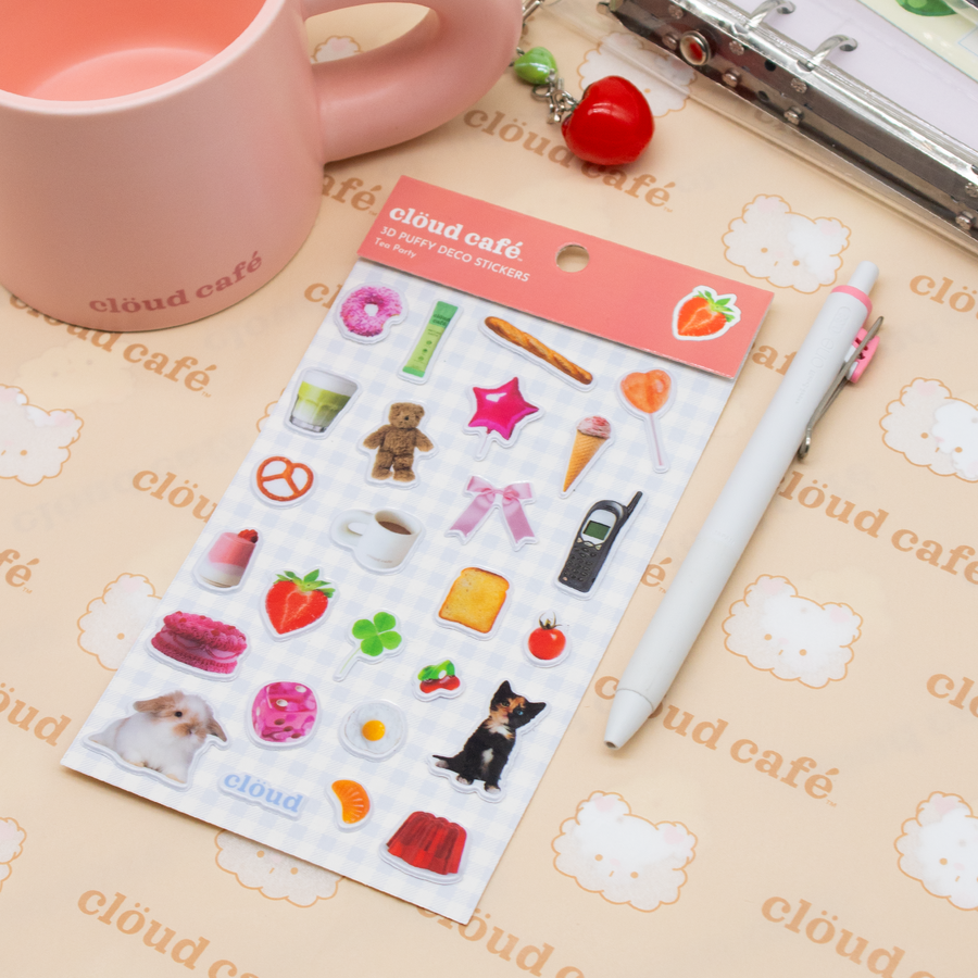 Sheet of stickers with various small images on a Clöud Café  branded surface with a pen and mug