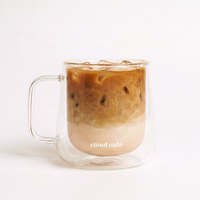 Back of a clear "Happy Sunday" mug showing the Clöud Café logo text with collagen iced coffee served over ice behind a white background