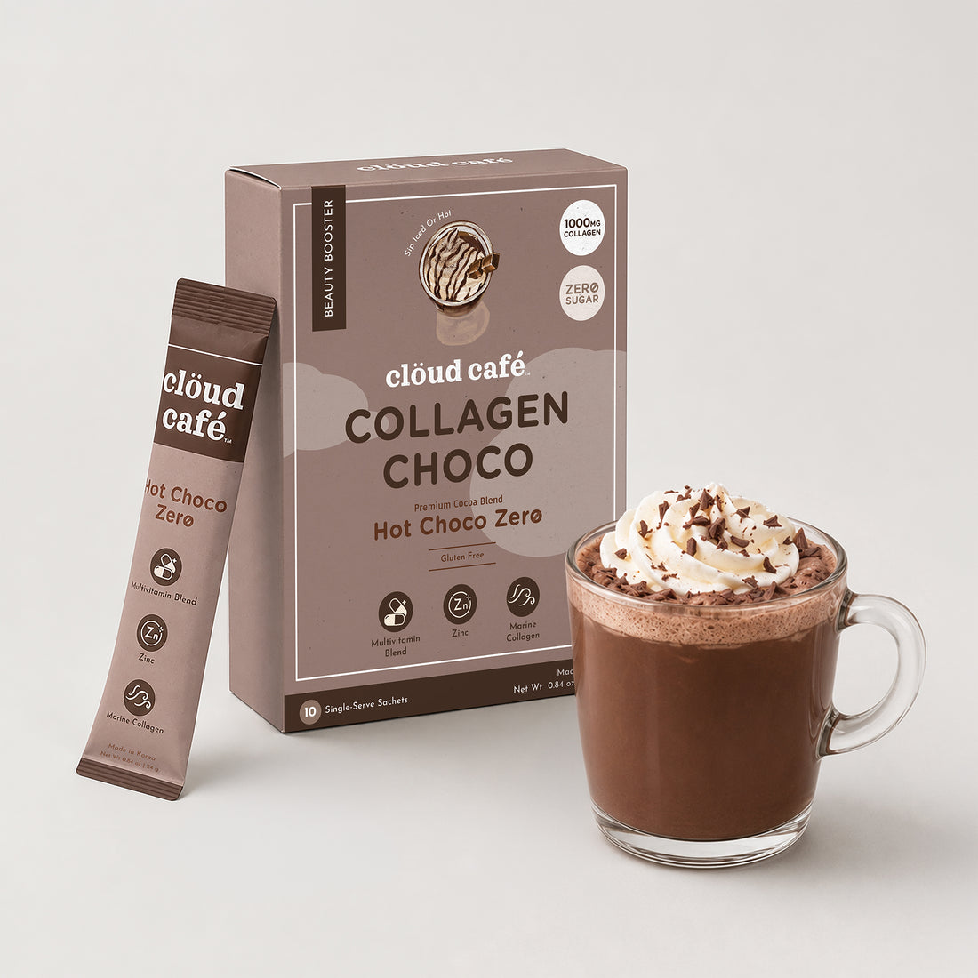 Clöud Café Collagen Hot Choco Zero instant sachet box with hot chocolate topped with whipped cream and chocolate shavings in clear glass mug, featuring 1000mg marine collagen, zinc, and multivitamin blend, zero sugar gluten-free Korean instant premium cocoa blend, 10 single-serve sachets.