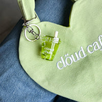 Clöud Café iced matcha shaker keychain hanging on a pastel green canvas tote bag.
