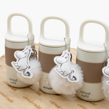 Three Hydra tumbler bottles with fluffy keychains and Moomin character keychain tags on brown Clöud Café branded paper