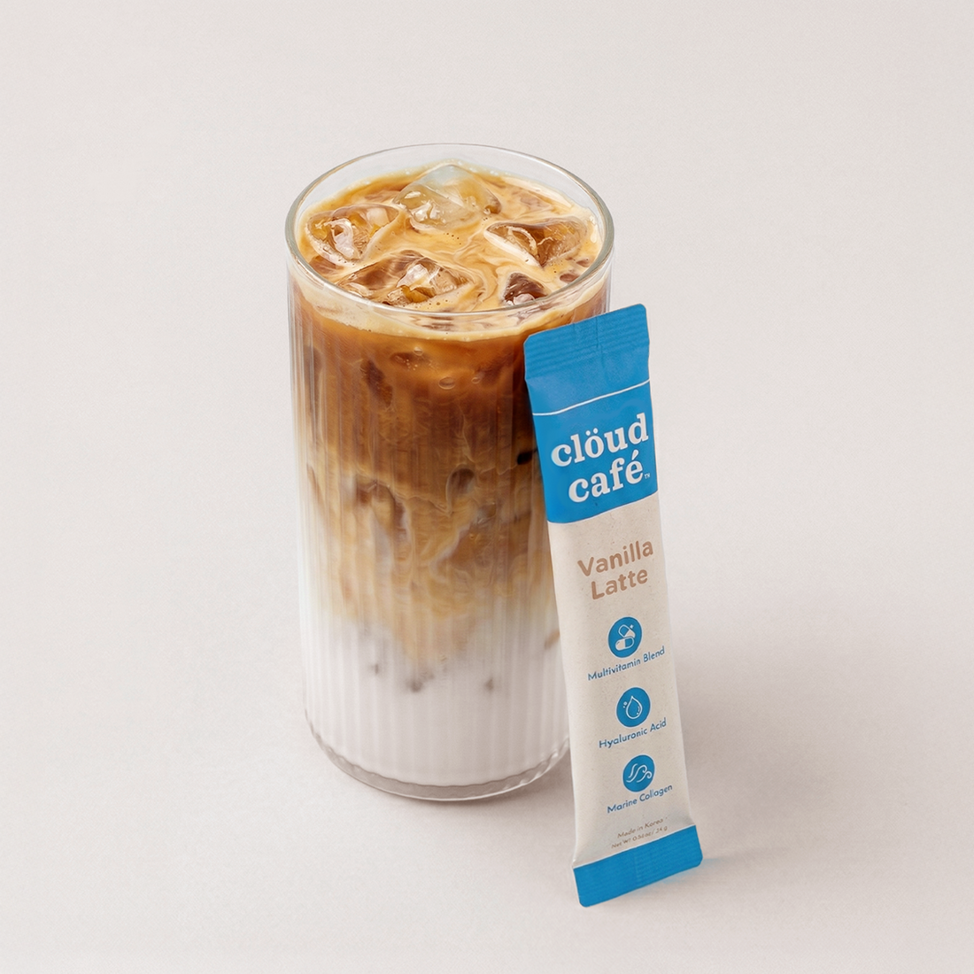 Glass of iced coffee with a Cloud Cafe vanilla latte packet on a white background