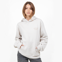 Model wearing light cream hoodie with minimal clöud café logo on the chest.