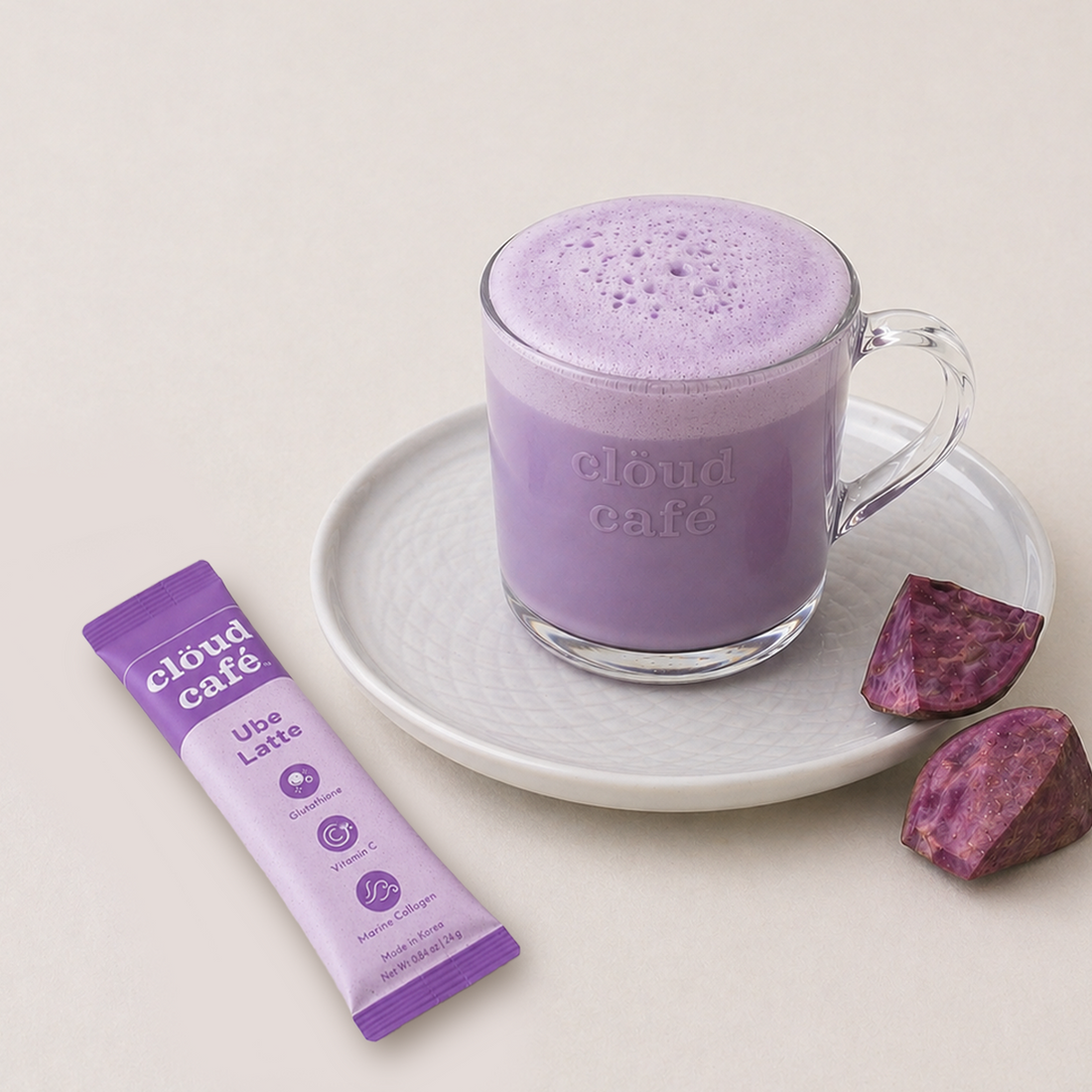 Purple ube latte in a clear mug with a cloud cafe package on a light background